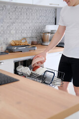 Man taking clean dishes out of dishwasher