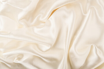 Background of a beige satin textile with waves and wrinkles. It can serve as wallpaper or web. Can be used to present products