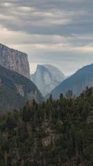 Keuken foto achterwand Half Dome Vertical shot of the Half Dome in Yosemite National Park with cloudy sky and thick forests in front