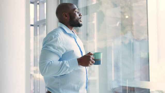 Drinking Coffee, Getting Ready And Thinking With A Business Man Standing By A Window In The Morning At Home. Waking Up, Looking At The View And Thinking About The Work Day Ahead At His Office Job