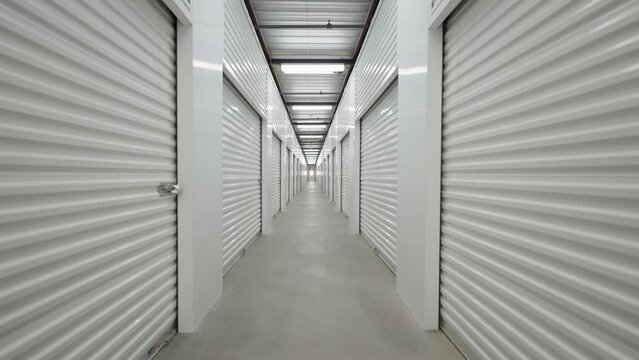 Interior shot down corridor with self storage units at storage facility using locked rolling garage doors.