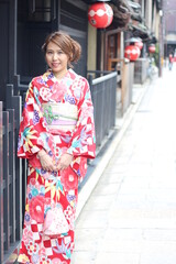 Fototapeta premium Portrait of beautiful woman wearing Japanese Kimono in front of a street in Kyoto, Japan