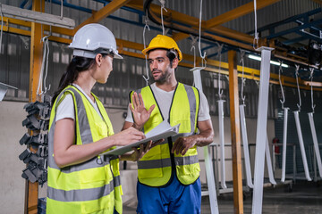 Caucasian male and Asian woman industrial work in manufacturing plant.