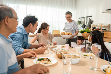 Asian big happy family having lunch on eating table together in house. 