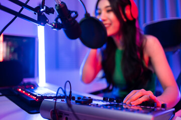 Obraz na płótnie Canvas Asian attractive audio DJ woman speaks into microphone to broadcasting