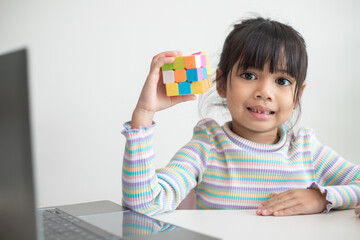 NAKHON RATCHASIMA, THAILAND - JULY 14, 2022:Asian little cute girl holding Rubik's cube in her...