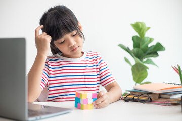 NAKHON RATCHASIMA, THAILAND - JULY 14, 2022:Asian little cute girl holding Rubik's cube in her...