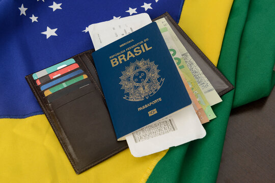 Brazilian passport over table with Brazilian flag in the background.