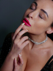 Obraz premium brunette with red lipstick on her lips in a black bodysuit on a gray background