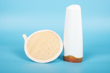 loofah washcloth and shampoo on blue background, washing accessories.