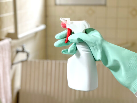 お風呂掃除をするビニール手袋をして洗剤を持つ手