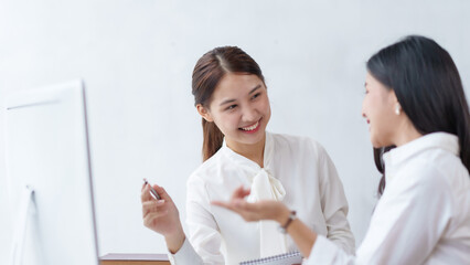 Fototapeta premium Two beautiful Asian young business women discuss work exchange idea exchange knowledge using laptop computer in the office.