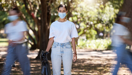 Female wearing covid mask cleaning the park for a clean, hygiene and safe green outdoor environment. Community service, volunteers or activist workers with rubbish, trash and garbage in a plastic bag