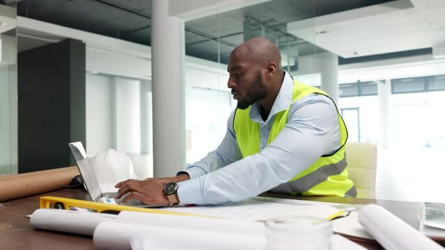 Architect, building planner or construction worker typing on a laptop, planning and drawing blueprints for a building or construction project. Replying, reading and sending email of new development.