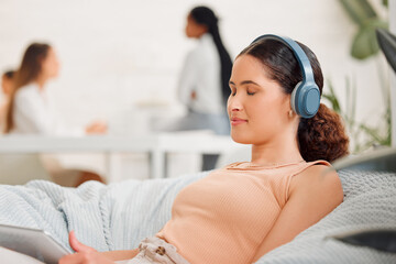 Rest, relaxation and break with a modern and creative design professional listening to music with wireless headphones on a beanbag chair. Young business woman resting in her office for mental health