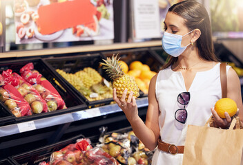 Woman grocery shopping while wearing a mask for medical protection against covid in a supermarket. Young female buying healthy, organic and wellness fruit consumables at a food store.