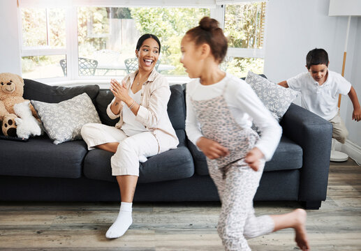 Playing, Running And Young Children Excited Indoors With A Smiling Mother Watching On A Couch. Happy Family Spending The Day Together Indoors While The Active Kids Run, Play And Have Fun At Home