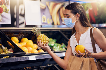 Shopping, holding and looking at fruit at shop, wearing mask for safety and protecting from covid at a grocery store. Young woman buying healthy produce, choosing items and examining at market