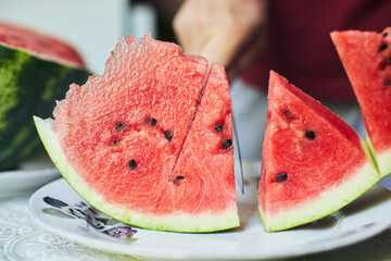 Juicy red watermelon is cut with a knife. The concept of summer and delicious vegetables. Front...