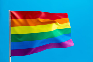 Rainbow flag waving on blue background