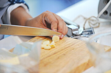 Almaty, Kazakhstan - 08.28.2015 : Slicing garlic slices on a wooden board in the kitchen.