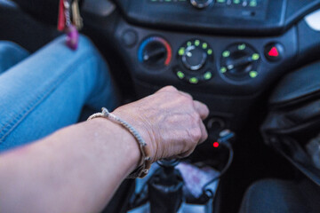 Close up of Latin adult woman hand on car shift while driving on the road. Copy space.