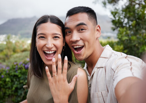 Engagement, ring and celebration with a young couple announcing their happy news and special occasion. Closeup portrait of a man and woman taking a selfie after getting engaged to be married outside
