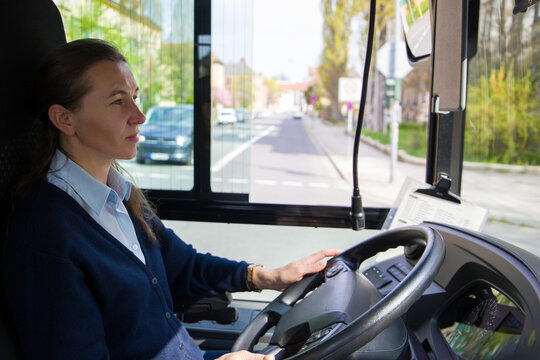 A Woman Bus Driver Is Driving A Bus