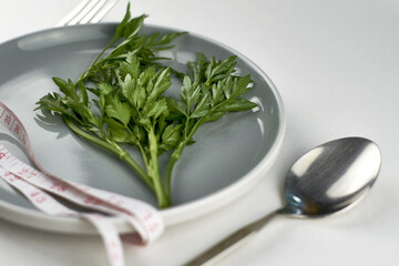 a plate of greens wrapped with a measuring tape next to a fork and spoon the concept of vegetarianism veganism diet