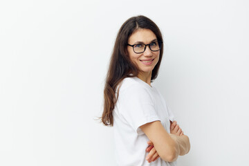 Fototapeta premium joyful cute woman stands in a white tank top and glasses for vision sideways with her arms crossed on her chest, with an empty space in the background for inserting an advertising layout