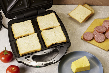 sandwich maker cheese sausage and bread on the table