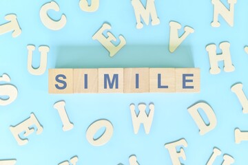 Simile figure of speech concept in English grammar class lesson. Wooden blocks typography flat lay in blue background.