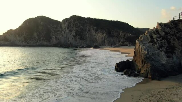 Foamy Waves Splashing On The Sandy Shore Of Playa Maruata In Michoacan, Mexico At Sunset - drone shot
