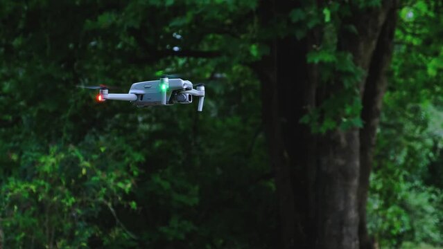 A view of a drone flying with green backgroun of trees. Static shot. Green constrast color.