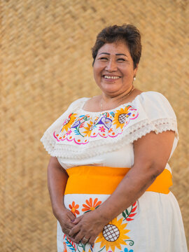 Vertical portrait of an Indigenous woman smiling while looking directly into the camera 