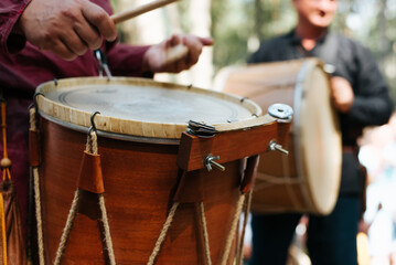 Fototapeta na wymiar Close-up of a musician playing an ethnic drum with percussion folk music at a traditional medieval outdoor entertainment. Selective focus on percussion