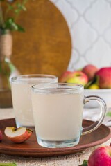 White kvass, a fermented drink made from apples in glass mugs on a light concrete background. Fermented foods, probiotics.