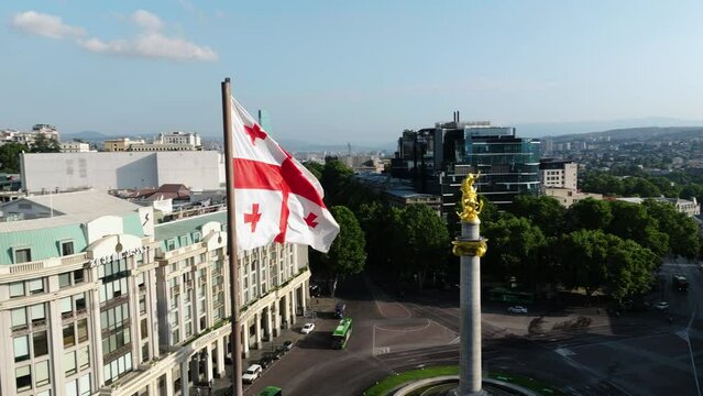 Georgian Flag On The Flagpole Waving At The Freedom Square In Tbilisi, Georgia With St. George Monument In Background. drone orbit