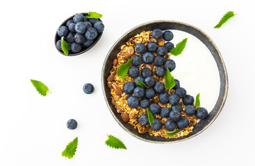 Homemade granola with yogurt, blueberries and mint leaves in a bowl on a white background, delicious healthy breakfast
