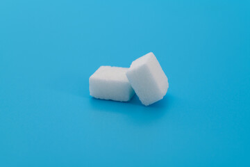 Two sugar cubes on blue background