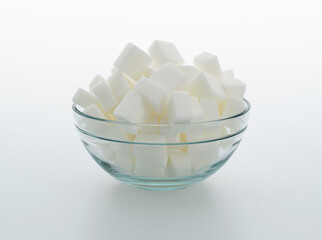 Sugar cubes in a bowl on white background