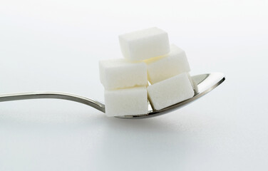 Sugar cubes in a spoon on white background