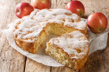 Freshly baked apple pie charlotte sprinkled with powdered sugar close-up on an old wooden table. horizontal