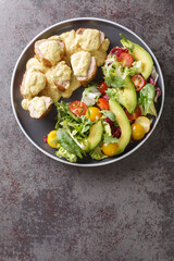 Sliced pork tenderloin served with honey mustard sauce and fresh vegetable salad close-up in a plate on the table. Vertical top view from above
