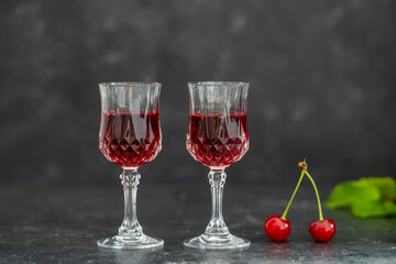 Homemade cherry brandy in two crystal glasses on a black background