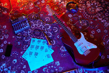 Top view background of electric guitar and music notes on ornate carpet in home studio, copy space
