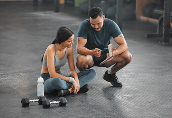 Fototapeta na wymiar Personal trainer, coach or fitness instructor helping an active and fit woman in the gym. Young female athlete sitting down and managing her workout routine or schedule with her exercising partner