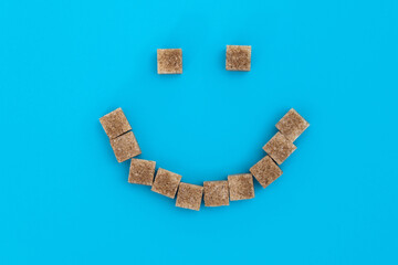 Smile face made of brown sugar cubes - obrazy, fototapety, plakaty