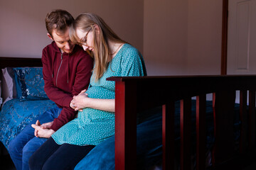 Young christian couple praying together in bedroom for unborn baby