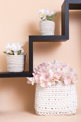 Knitted home interior decor handmade. Crocheted decorative baskets made of natural material cotton on a shelf with flowers to decorate the room. Hobby and needlework, handicrafts